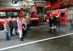 Dzieci obserwują działanie węża strażackiego.
